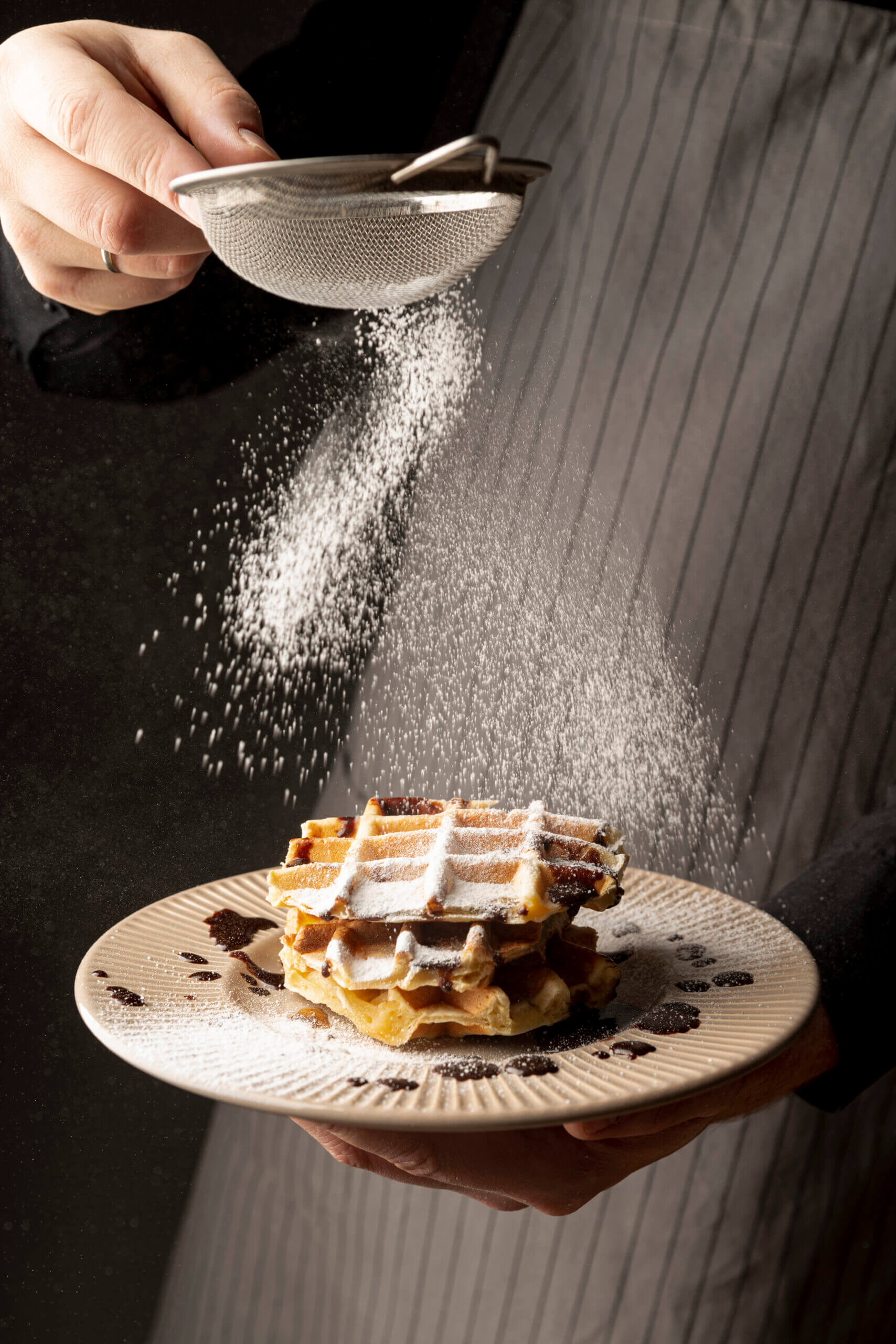 front-view-man-coating-waffles-with-powdered-sugar